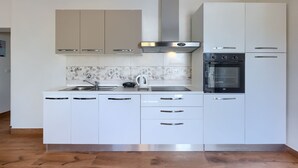 A modern kitchen with white cabinets, a stainless steel range hood, a built-in oven, and a dishwasher. - Chill out . (Marcana)
