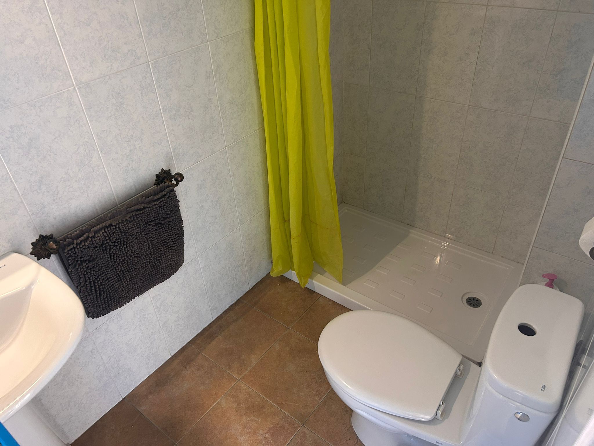 A bathroom with a toilet, sink, and shower area.