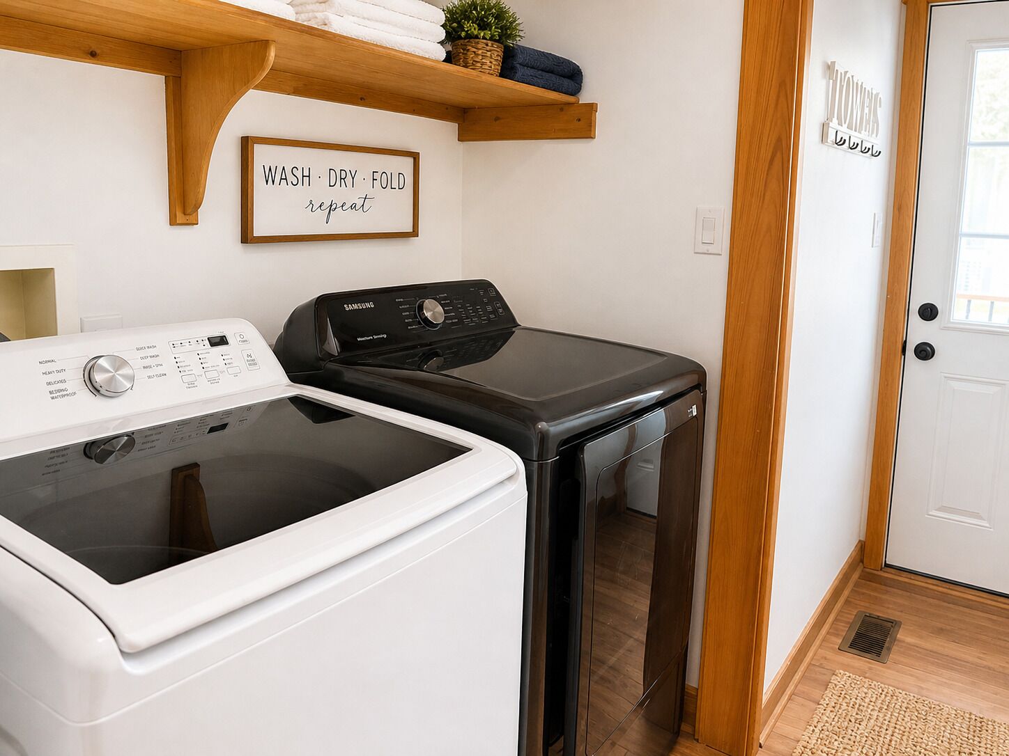A laundry area with a washing machine, dryer, and a sign that says 'WASH DRY FOLD repeat.'