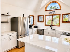A modern kitchen with a stainless steel refrigerator, a coffee maker, and a sign indicating fresh daily catch.