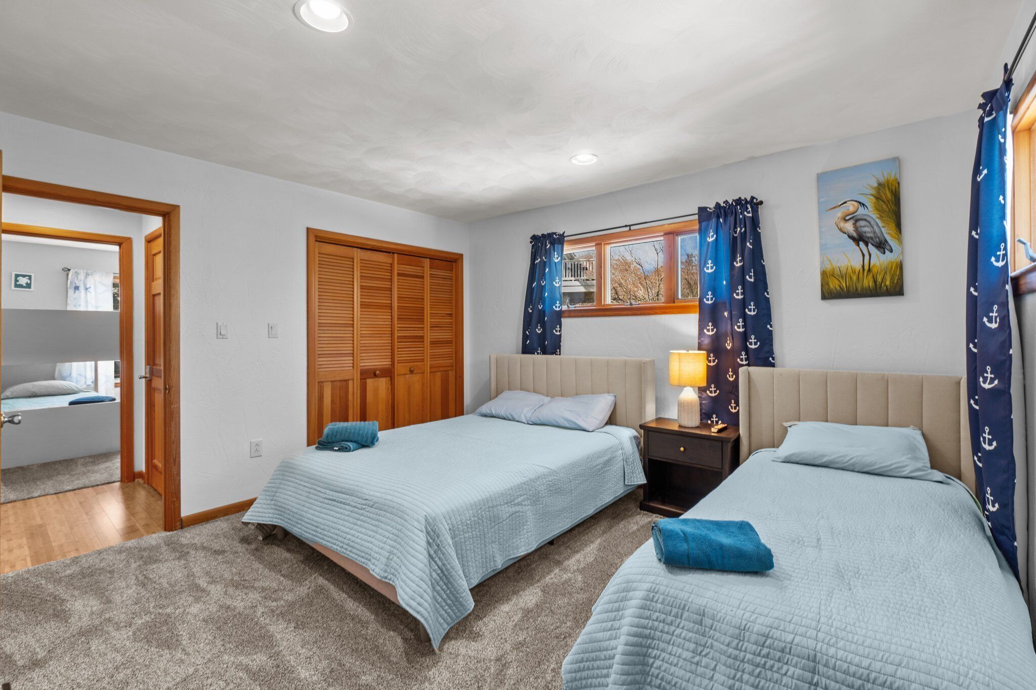 Ein Schlafzimmer mit zwei Betten, einem Holzschrank, einem Fenster mit Vorhängen und einem Bild an der Wand.