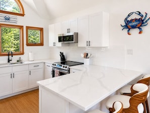 Una cocina moderna con armarios blancos, una isla grande, un microondas y un fregadero.