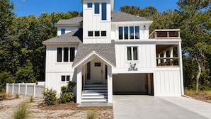 Ein zweistöckiges Haus mit Garage, überdachter Veranda und einer kleinen Terrasse.