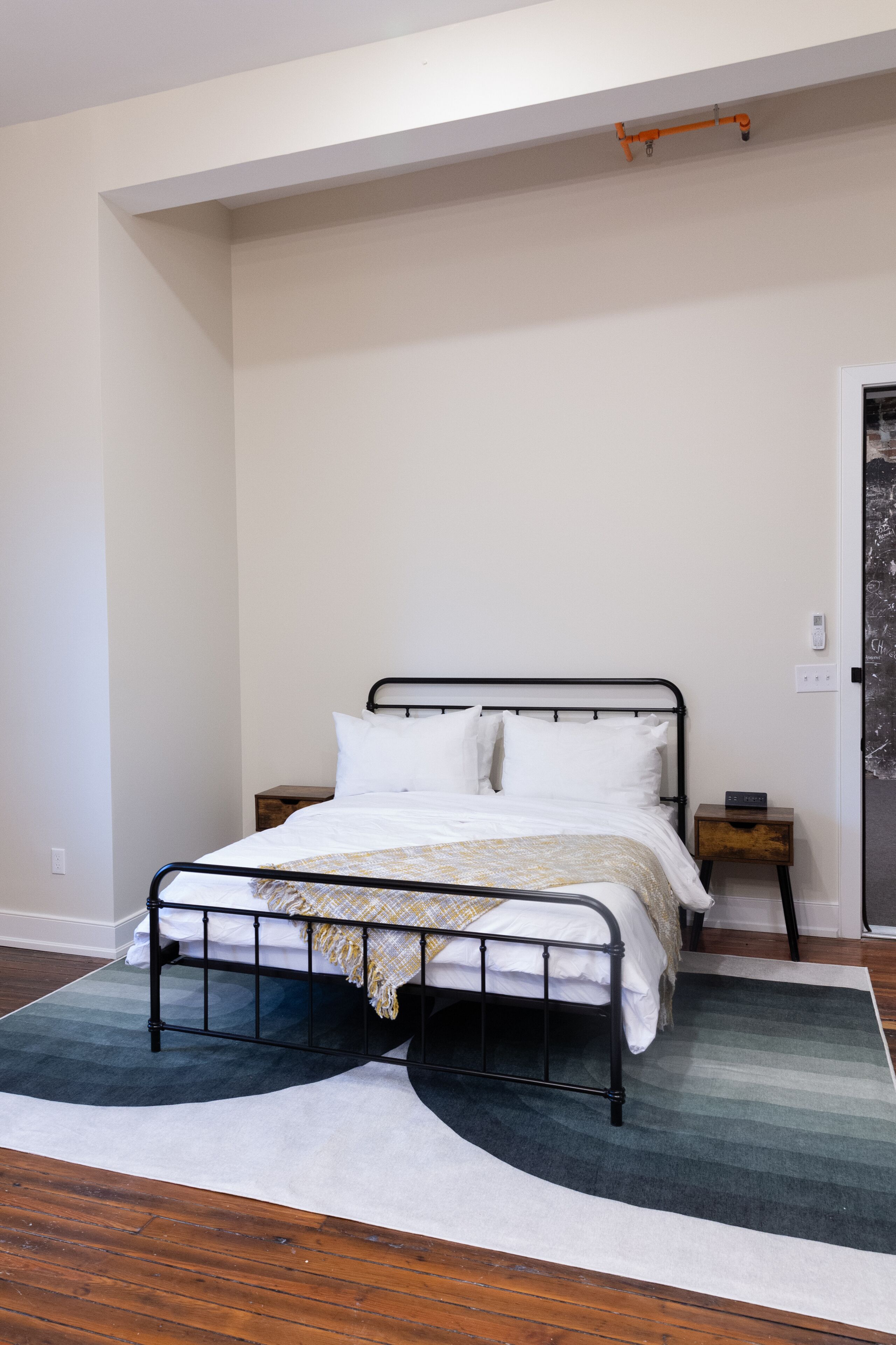 A neatly arranged bedroom with a bed, a nightstand, and a wall-mounted light fixture.