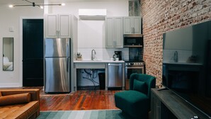 A modern kitchen with stainless steel appliances, a brick wall, and a cozy seating area. - The St. Clair (Frankfort)