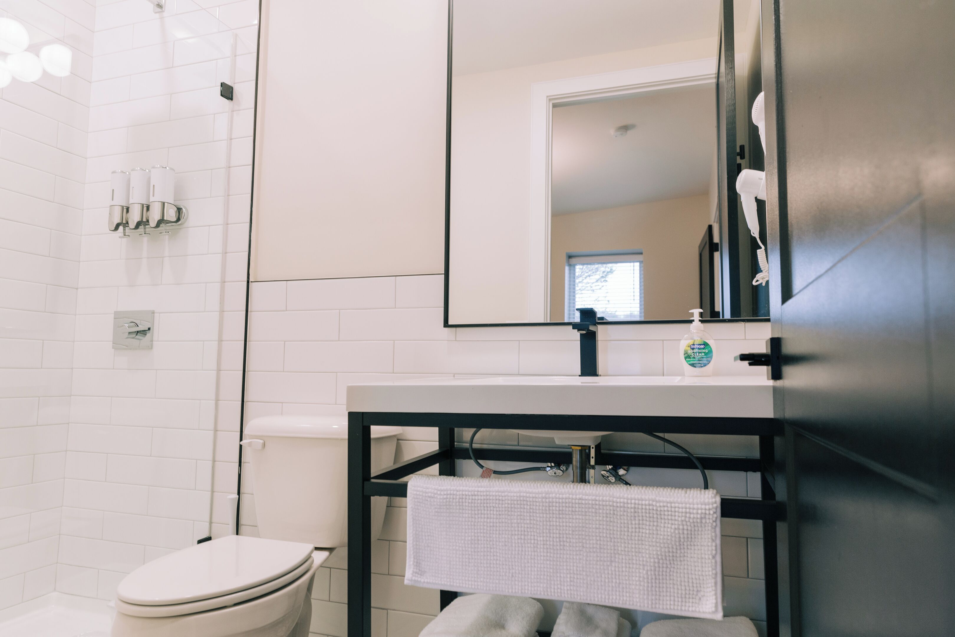 A modern bathroom with a white toilet, a black sink vanity, and a large mirror.