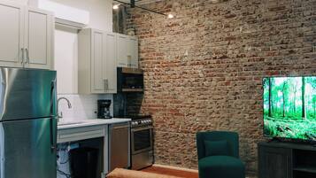A modern kitchen with a brick wall, stainless steel appliances, and a dining area with a bench and table.