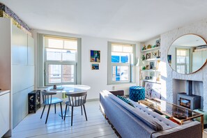 A modern living room with a sofa, a round dining table with chairs, and a fireplace. - Notting Hill, 1 Bed, Sleeps 2, Wifi (London)
