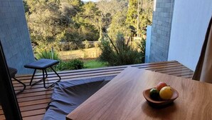 Ein Holztisch mit Obstschale auf einem Balkon mit Blick auf einen Garten.