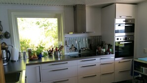 A modern kitchen with white cabinets, stainless steel appliances, and a window providing natural light.