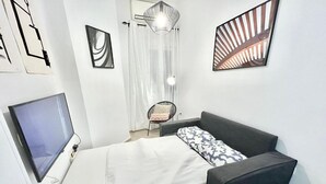 A modern bedroom with a bed, a TV, a chair, and artwork on the walls. - Centro Ronda de Segovia Aparment (1 bedroom apartment) (Madrid)