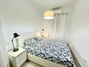 A bedroom with a bed, two bedside lamps, a nightstand, a hanging lamp, and a window with curtains. - Centro Ronda de Segovia Aparment (1 bedroom apartment) (Madrid)