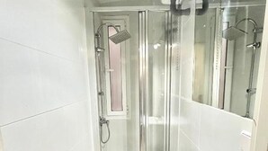 A modern bathroom with a glass-enclosed shower, a white sink, and a mirror. - Centro Ronda de Segovia Aparment (1 bedroom apartment) (Madrid)