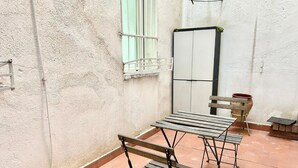 A small patio area with a wooden table and chairs, a window, and a white door. - Centro Ronda de Segovia Aparment (1 bedroom apartment) (Madrid)