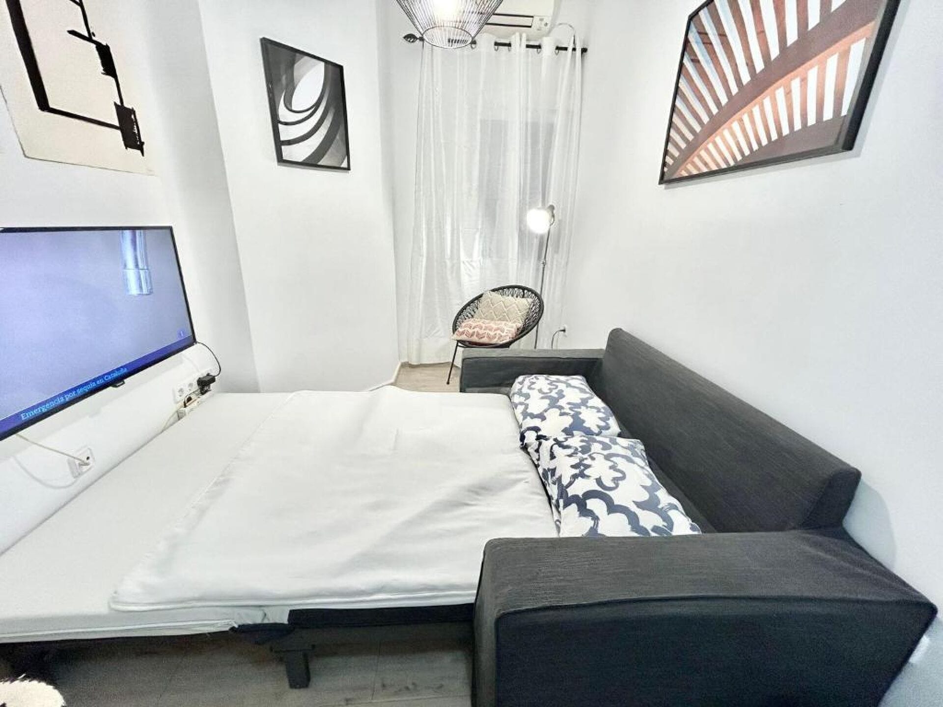 A bedroom with a bed, a chair, a desk, and a TV.