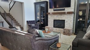 A living room with a fireplace, leather sofas, a glass coffee table, and a staircase. - Snowcreek Resort Vacation Rental 1431 (Mammoth Lakes)