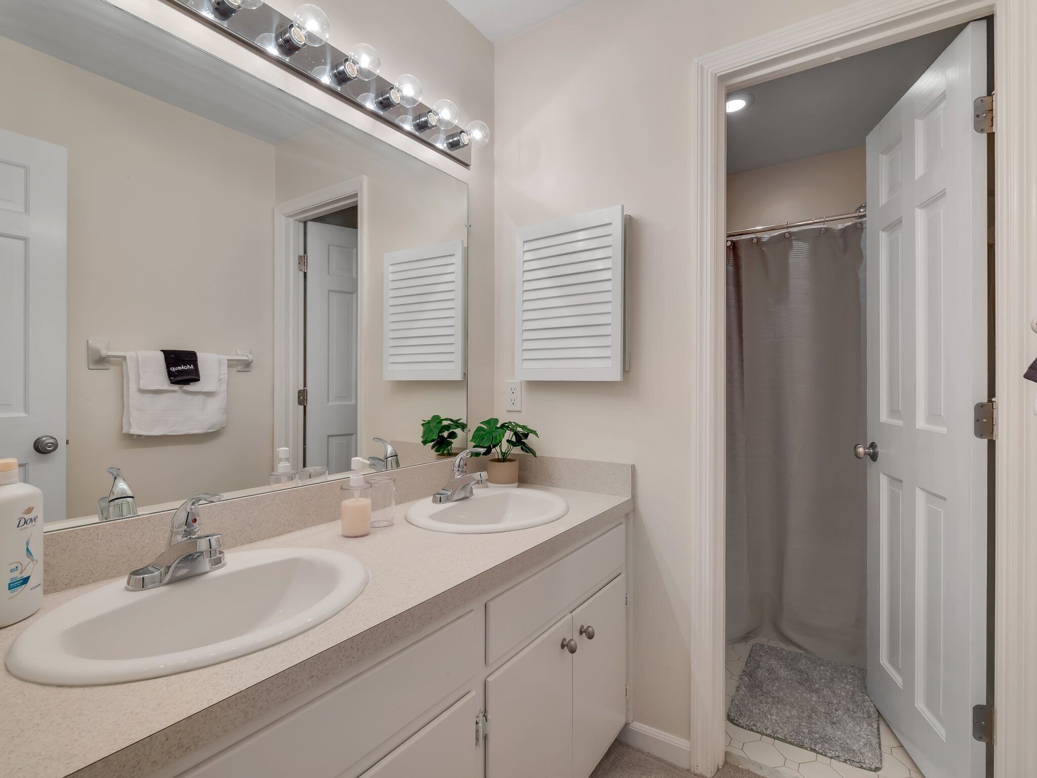 A bathroom with two sinks, a large mirror, and a shower curtain.