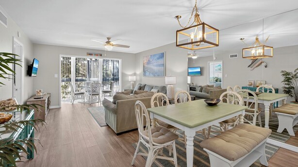 A spacious living area with a dining table, chairs, and a ceiling fan. - VH 206C (Siesta Key)