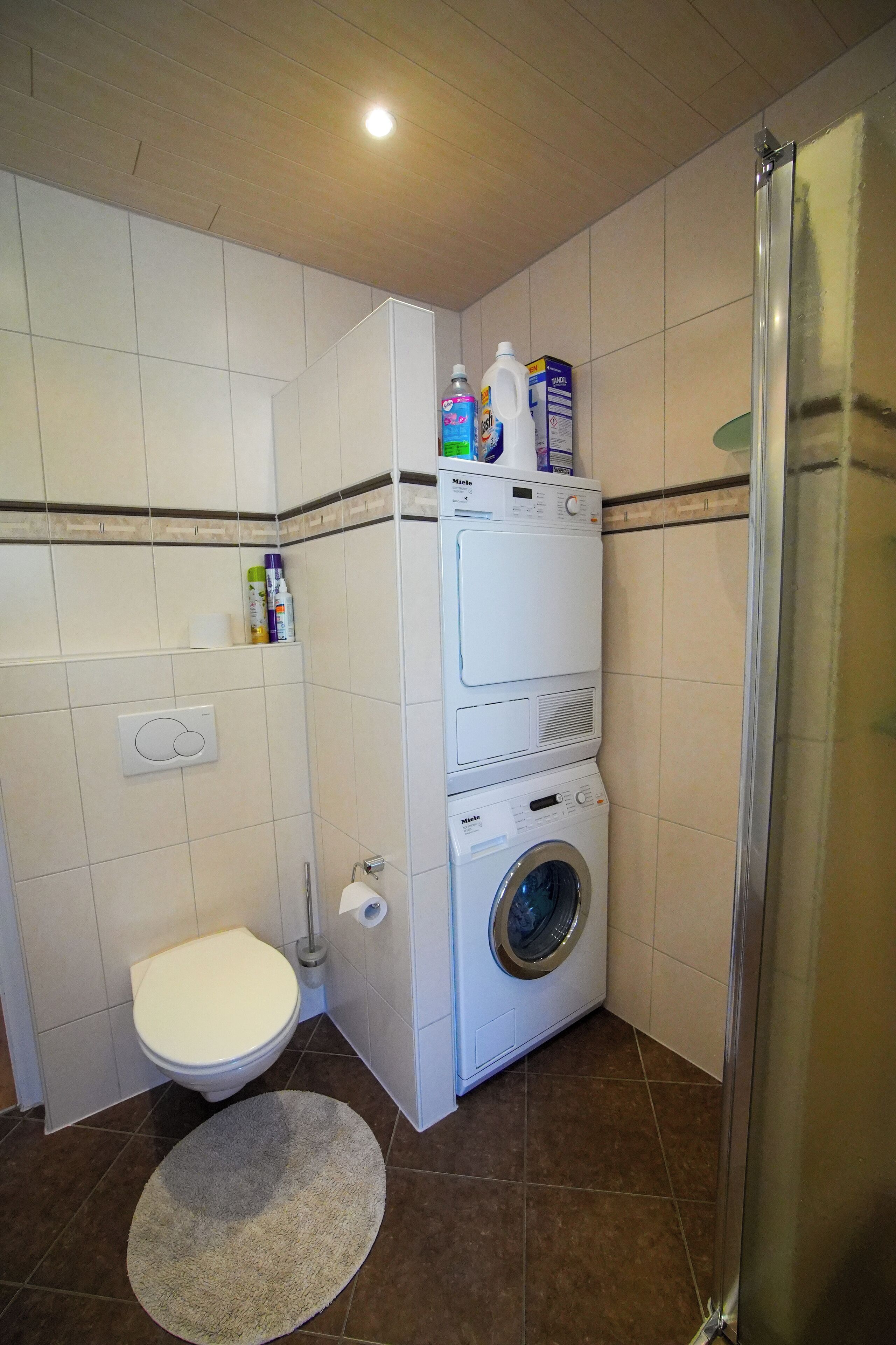 Ein kleines Badezimmer mit Toilette, Waschmaschine und Duschkabine.