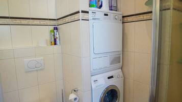 Ein kleines Badezimmer mit Toilette, Waschmaschine und Duschkabine.