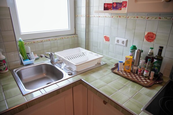 A kitchen with a sink, a dish rack, and various kitchen items on the counter.
