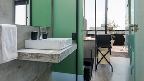 A modern bathroom with a concrete sink, a green partition, and a view of the outdoors.