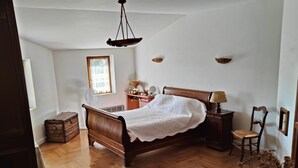Un dormitorio con una cama de madera, un aparador, una silla y una mesita de noche con una lámpara.