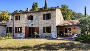 Una casa de piedra con un patio, mobiliario exterior y vistas del paisaje circundante.