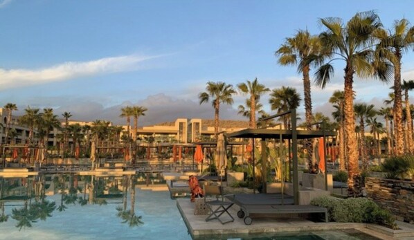 Relax by the resort pool surrounded by lush palm trees and modern architecture.
