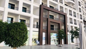 A multi-story hotel with balconies, a central entrance, and a landscaped courtyard. - Porto Dead Sea  (Sweimeh)