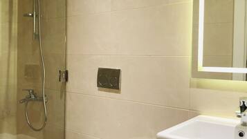 A modern bathroom with a glass-enclosed shower, a white toilet, and a sink with a dark countertop.