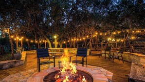 Eine Terrasse im Freien mit Feuerstelle, Sitzgelegenheiten und Lichterketten.