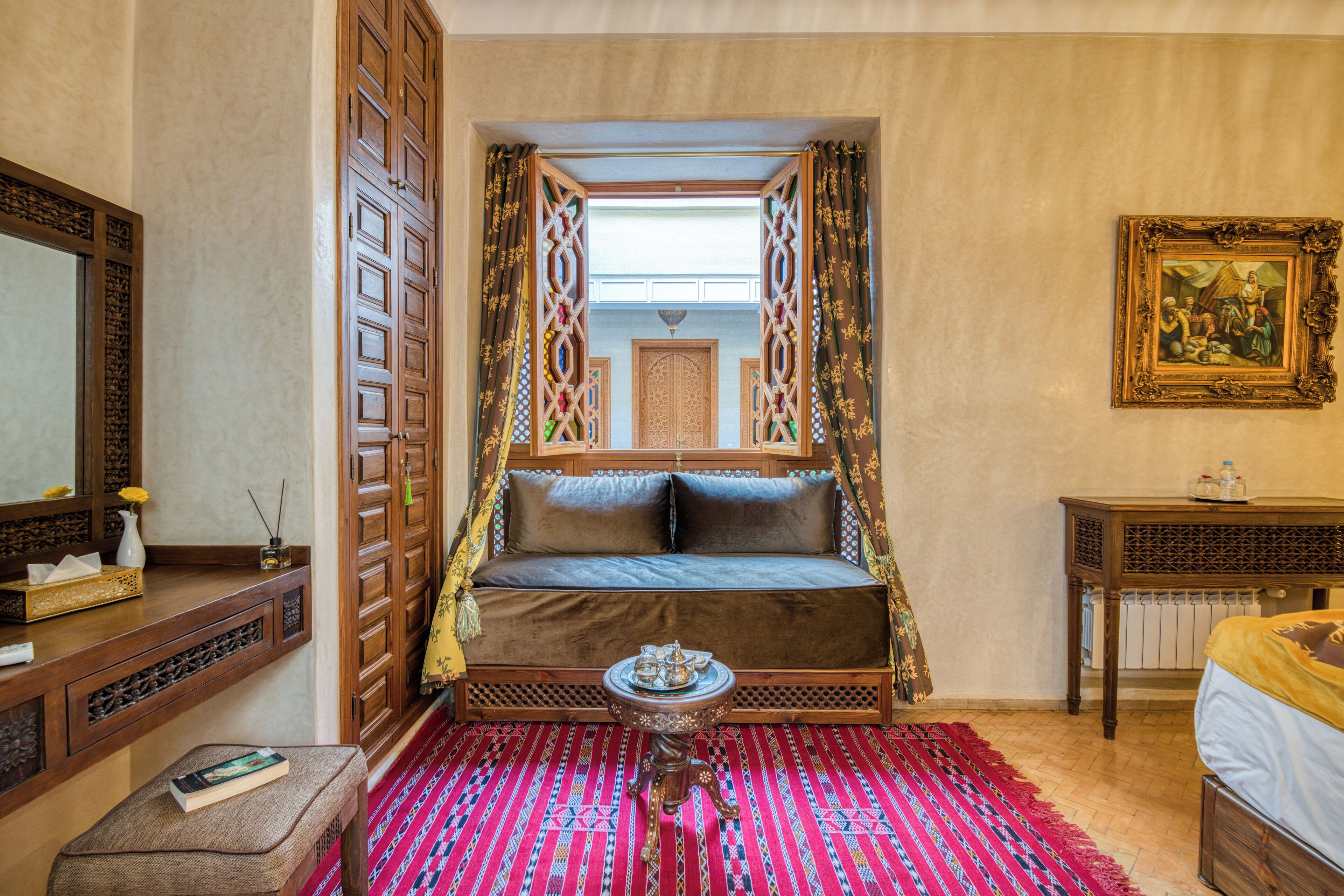 A traditional room with a sofa, a small table, a mirror, and a framed picture on the wall.