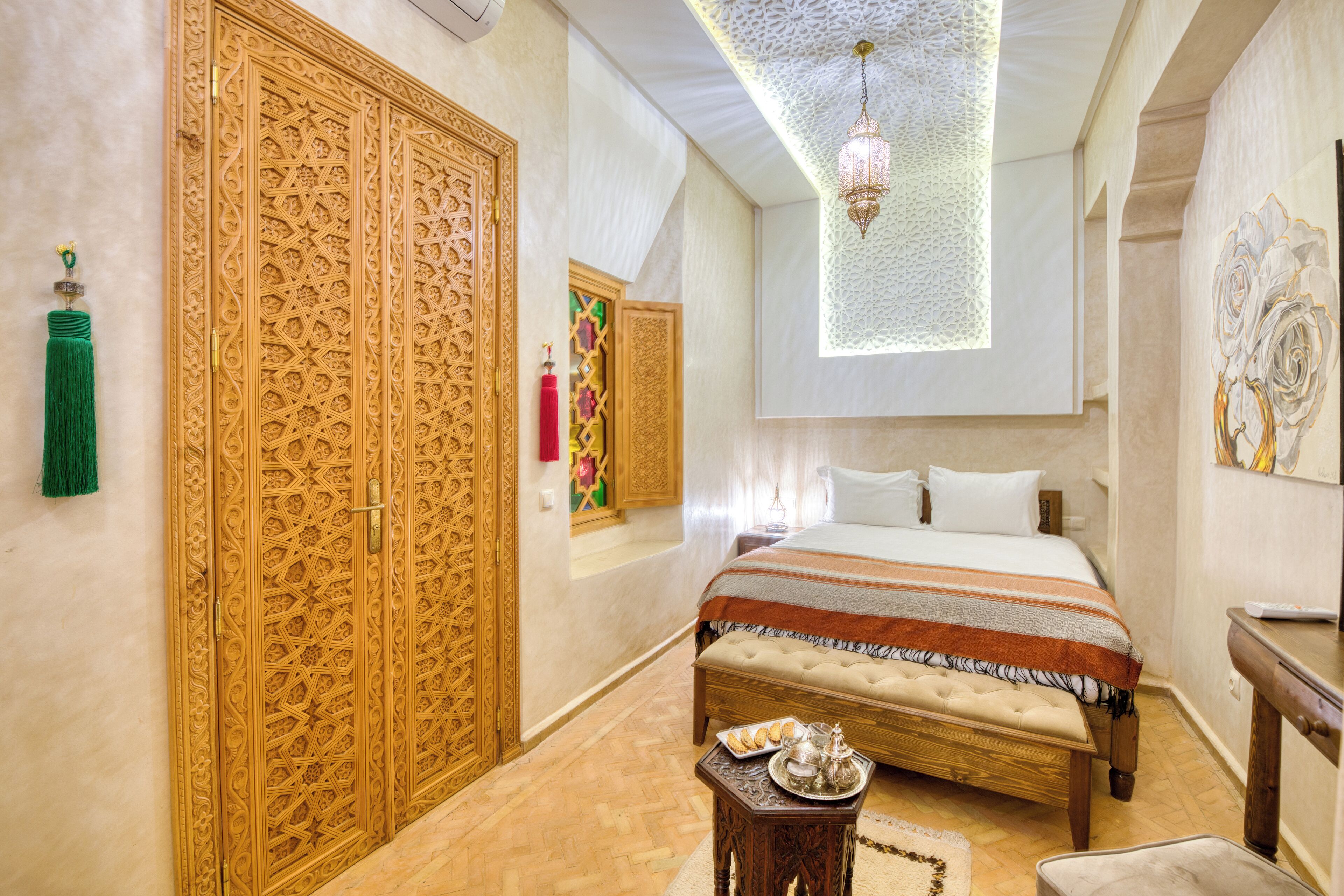 A bedroom with a large bed, a wooden wardrobe, and a small table with a tray.