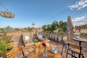 Une terrasse sur le toit, aménagée avec des sièges, une table et des plantes en pot.