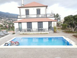 En toetages bygning med swimmingpool, balkon og udsigt over en by i baggrunden.