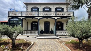 A two-story building with a symmetrical facade, featuring a central entrance with a black door, flanked by two columns. - Sea and Sun 4 You - Villa Oliveira (Funchal)