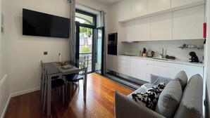 A compact living space with a dining area, kitchenette, and a sofa. - Sea and Sun 4 You - Villa Oliveira (Funchal)