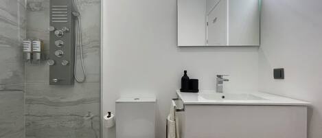 A modern bathroom with a shower, toilet, and sink.