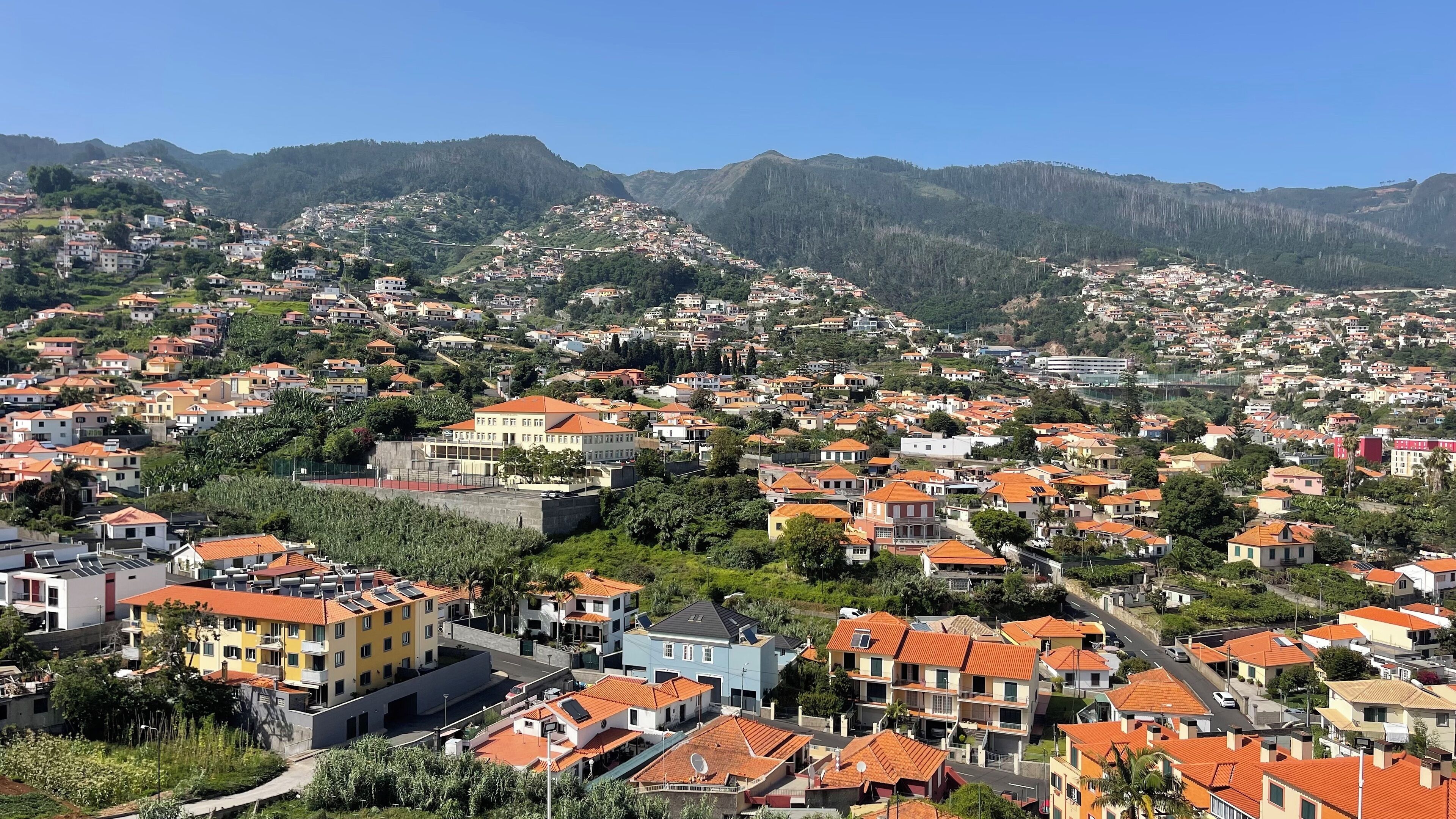 A residential area with houses and buildings, surrounded by hills.
