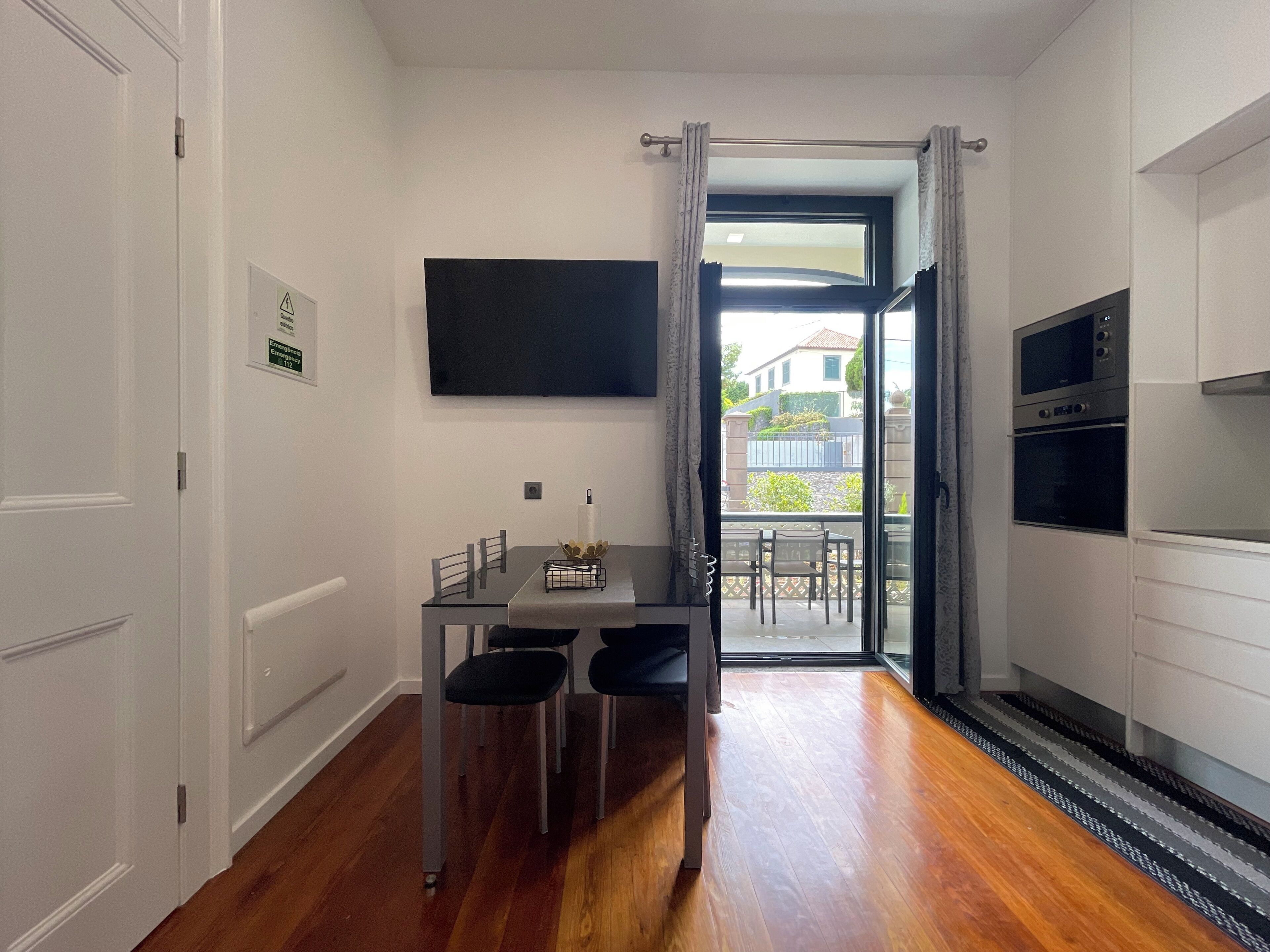 A compact kitchen with a dining area, a flat-screen TV, and a view of the outside.