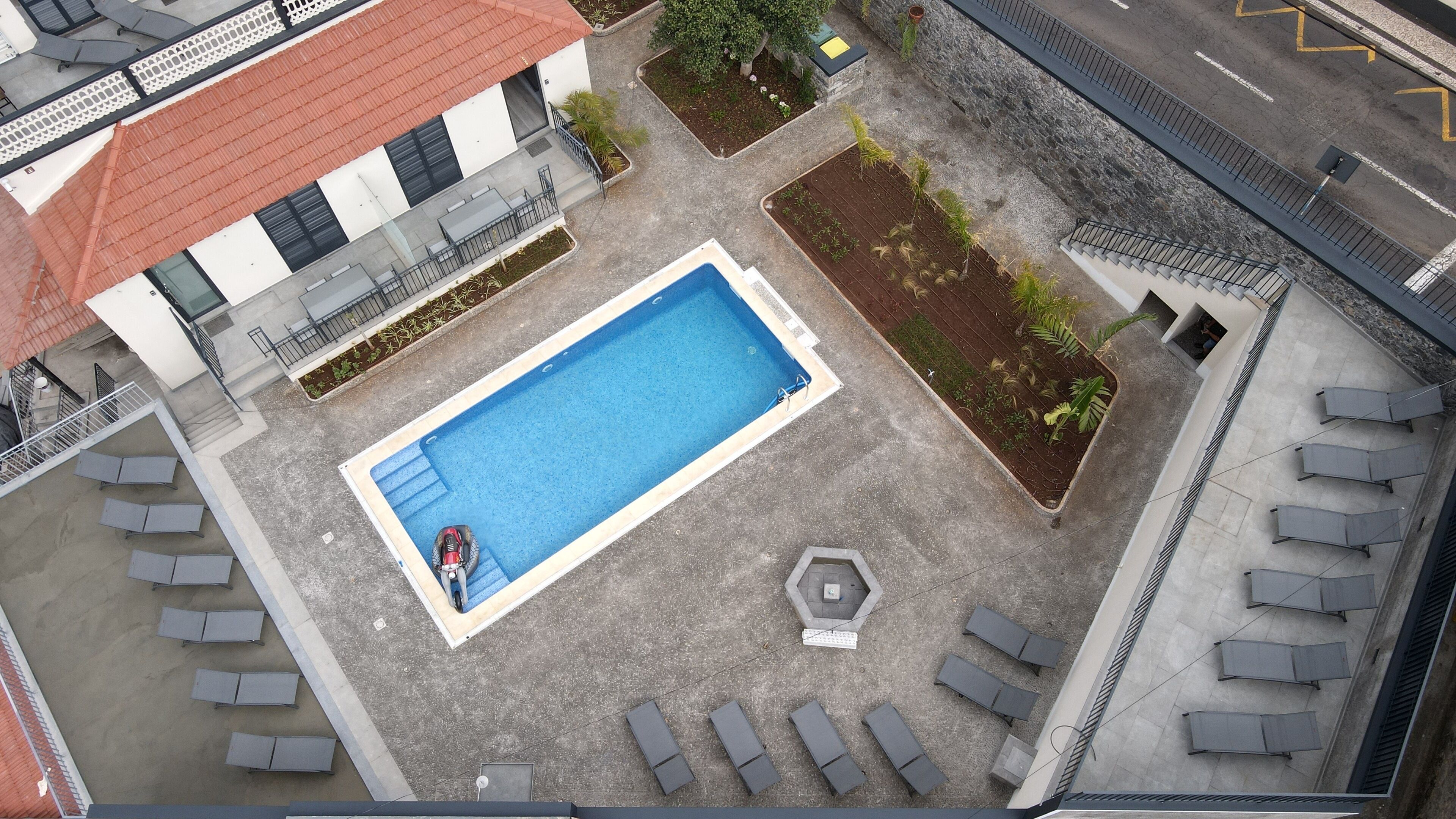 An aerial view of a swimming pool surrounded by lounge chairs and a garden area.