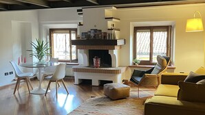 A spacious living room with a fireplace, a dining area with a glass table, and a cozy seating area with a sofa and armchairs. - Loft Albinelli in the heart of Modena (Modena)