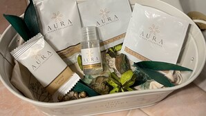 A bathroom sink area with a gold faucet, a white basin, and a white tray containing various toiletries including bottles labeled "AURA Luxury Collection." - Loft Albinelli in the heart of Modena (Modena)