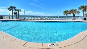 Une piscine d’un bleu éclatant, d’une profondeur de 1,20 mètre (avec un panneau indiquant qu’il est interdit de plonger), entourée de palmiers et offrant une vue sur la plage.