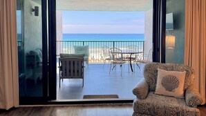 Une pièce dotée d’une porte-fenêtre coulissante donnant sur un balcon équipé de chaises de plage et d’une table.