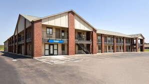 A two-story building with a brick facade, a sign for 'Travelodge,' and a parking lot. - Travelodge By Wyndham Wellington (Wellington)