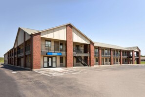 Un bâtiment à deux étages avec une façade en briques, une enseigne indiquant « Travelodge » et un parking.