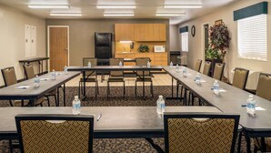 A conference room with tables, chairs, a refrigerator, a microwave, and a potted plant. - Travelodge By Wyndham Wellington (Wellington)