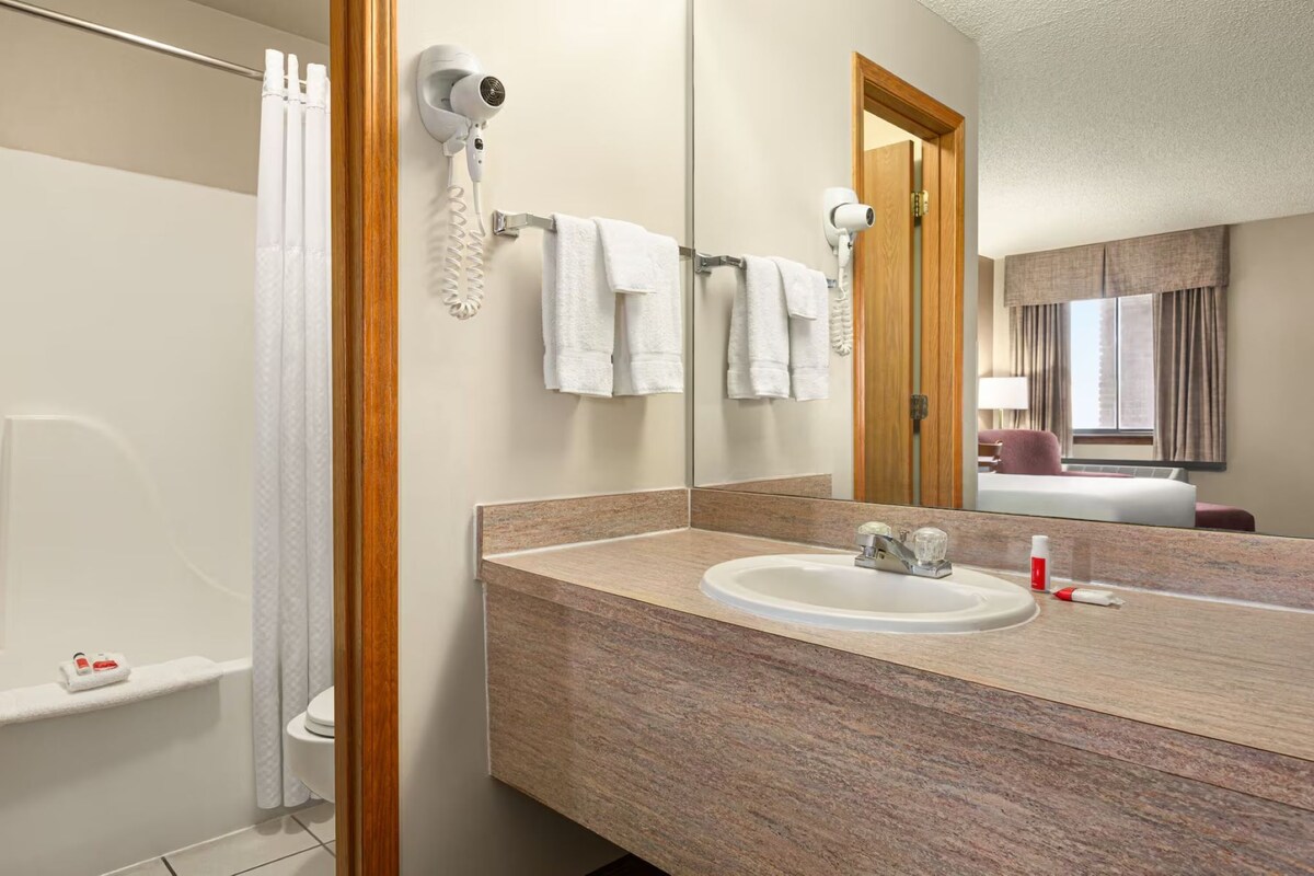 Une salle de bain équipée d’une douche, d’un lavabo, d’un sèche-cheveux et d’un miroir.